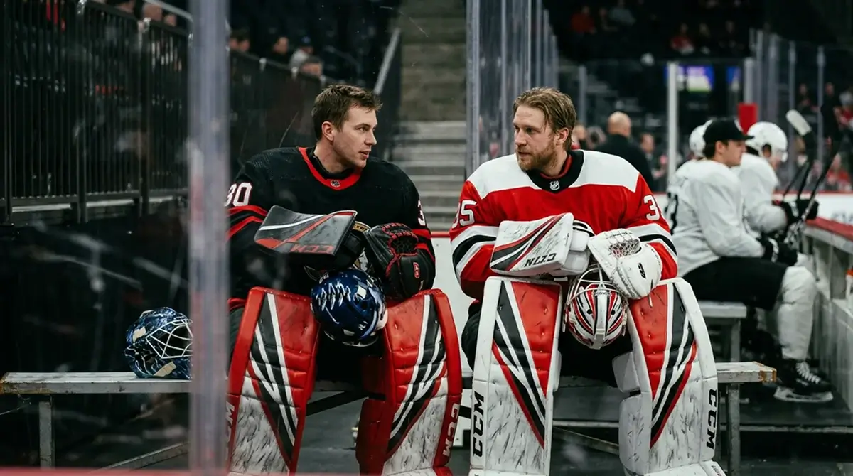 Two NHL tandem goaltenders talking on the bench between starts in a back-to-back